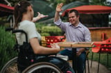 Child with Down syndrome in wheelchair with friend