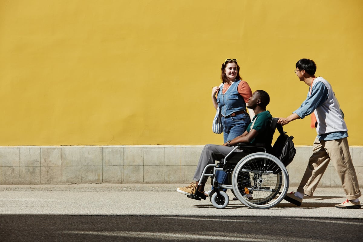 African American man in wheelchair with friends smiling outdoors